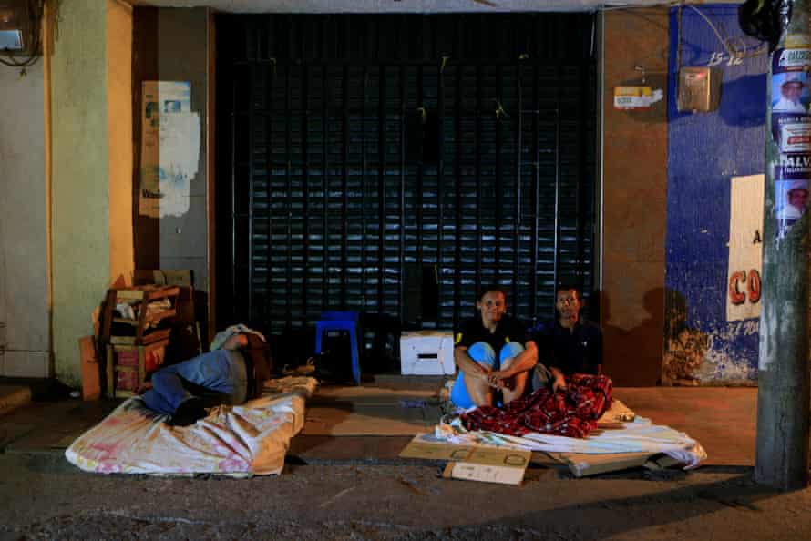 People sit on a makeshift bed on a Maicao street where Venezuelan immigrants gather to spend the night.