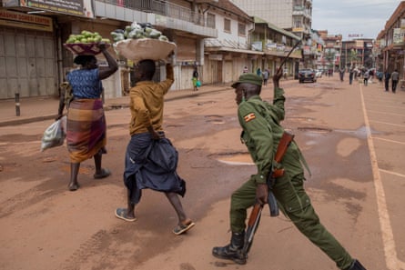 A police officer beats a female orange vendor on a street in Kampala, Uganda, on 26 March 2020
