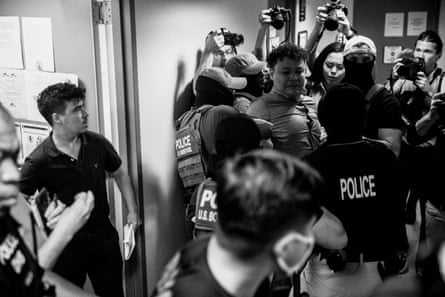 Masked agents force a man towards a staircase