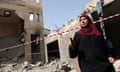 A Palestinian woman walks past a damaged house in Jenin