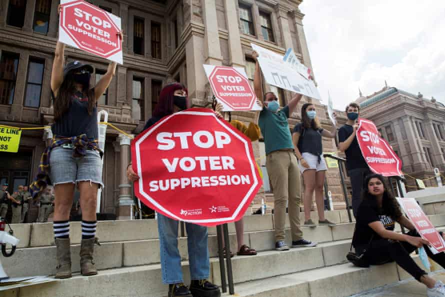 Protesters hold signs shaped like stop signs that read "Stop voter suppression".