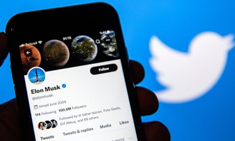 Elon Musk's Twitter account is seen displayed on a smartphone screen with a background of a twitter logo.