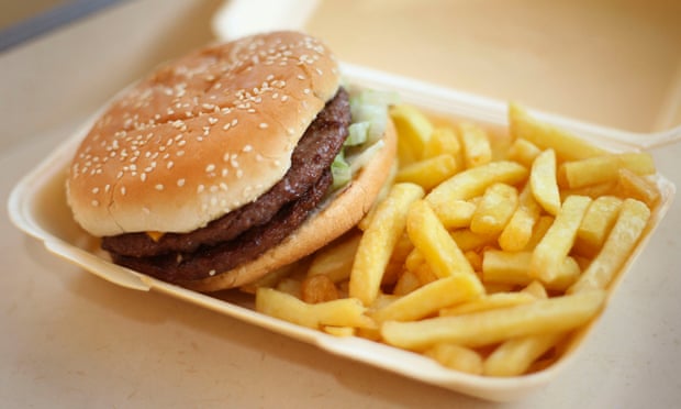 A half-pounder burger and chips in a takeaway carton