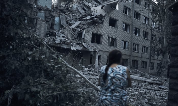 A Ukrainian woman walks amid the debris of a residential building following night shelling in Mykolaiv, Ukraine, Tuesday, Aug. 2, 2022. (AP Photo/Kostiantyn Liberov)