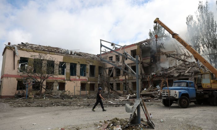 Ukrainian rescue workers use a crane as to move rubble out of a school building heavily damaged following shelling.