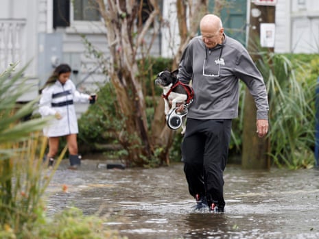 A man carries his pet dog along a flooded street as Ian attacks Charleston, South Carolina.