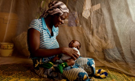 A mother in Burkin a Faso, where trials involving 450 children were held, protects her baby behind a mosquito net