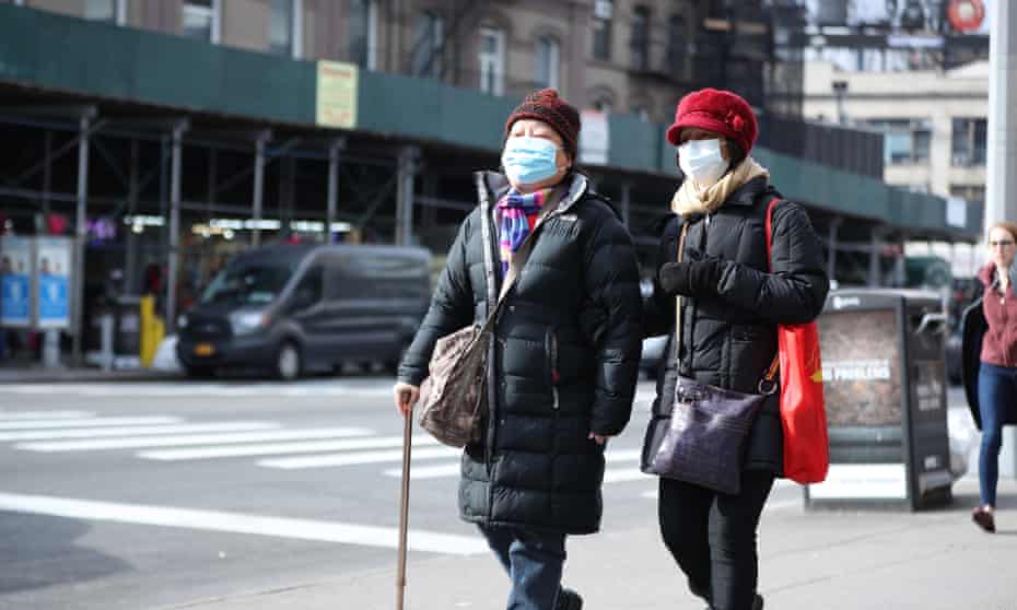 People wear medical masks as a precaution against coronavirus, walking around the in the streets of New York on Friday.