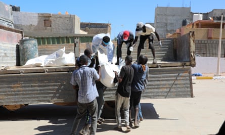 Rescue workers transport body bags with the remains of victims outside the hospital in Derna.