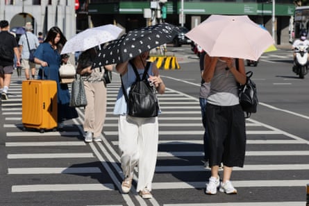 Pedestrians shield under umbrellas as they cross the street under scorching heat in Taipei, Taiwan.