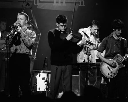 Four musicians in a black and white photograph, with one playing a violin and another a guitar