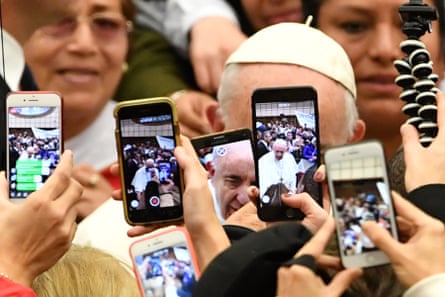 People greet Francis and take photos of him with their mobile phones