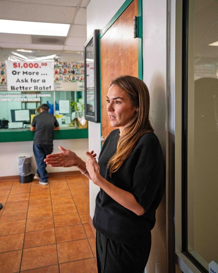 A business owner gestures with her hands as she speaks while one of her customers is visible in the background