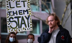 Refugees and supporters rally outside the  immigration department in Melbourne, holding a sign reading, 'Let them stay'.