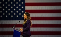 woman speaks at lectern in front of american flag