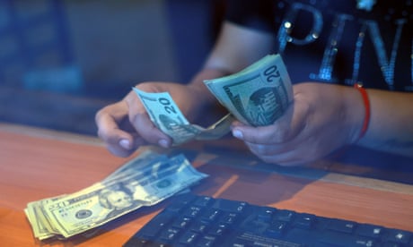 Someone counts out a stack of $20 bills at a currency exchange