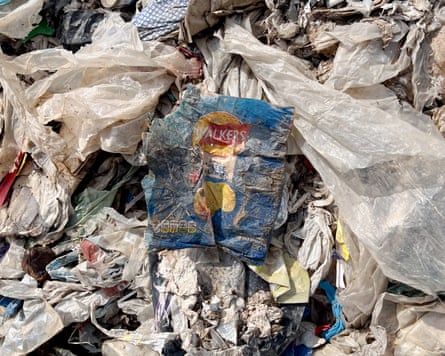 An empty Walkers crisps packet lying on a pile of dirty plastic bags