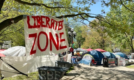 a group of tents on a lawn with trees around and a sign that reads liberated zone