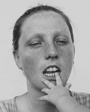 A woman with a baby's hand at her mouth