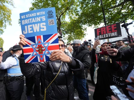 A protester from Our Fight holds up a sign reading ‘we stand with Britain’s jews’ with a union jack next to pro-Palestinian supporters