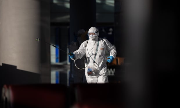 An airport worker in personal protection equipment sprays disinfectant at the departure gates area inside Beijing international airport.