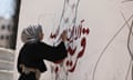 A Palestinian woman writes slogan over a map of Israel painted with an Arab keffiyeh imposed over it.