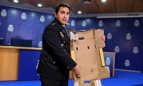 A Spanish police inspector displays a cocaine-impregnated fruit box at a press conference in Madrid