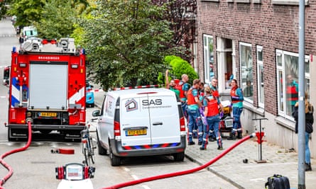 Members of the fire brigade and a fire engine and van next to a building