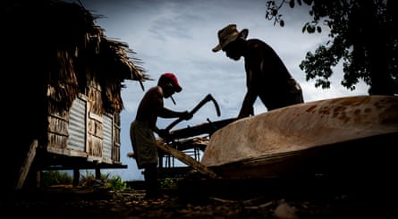 Men in Oibola carve a dugout canoe.