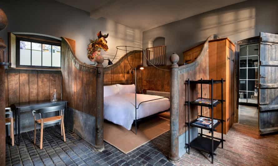A double bed with white bedding in an enclosure in a rustic room