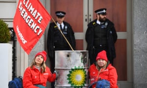 Police officers stand near activists locked to dirty oil barrels who blocked BP’s headquarters in London to mark the first day of the oil giant’s new chief executive.