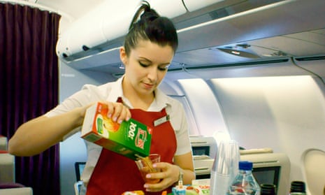 A female cabin crew member serves drinks on a Virgin Atlantic flight