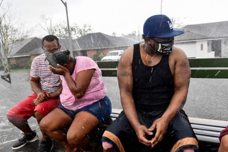 Darrin Heisser, right, reacts to a sudden rain shower as people evacuate from a flooded neighborhood in LaPlace, Louisiana, near New Orleans.