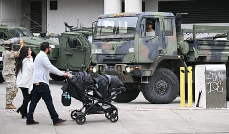 A couple pushes a stroller past members of the California Guard outside the Edward R. Roybal Federal Building.