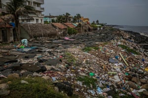 A woman lays out fish to dry in the sun on a sea wall in Puducherry