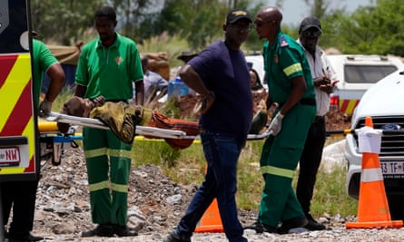 A miner is carried on a stretcher by rescue workers into an ambulance