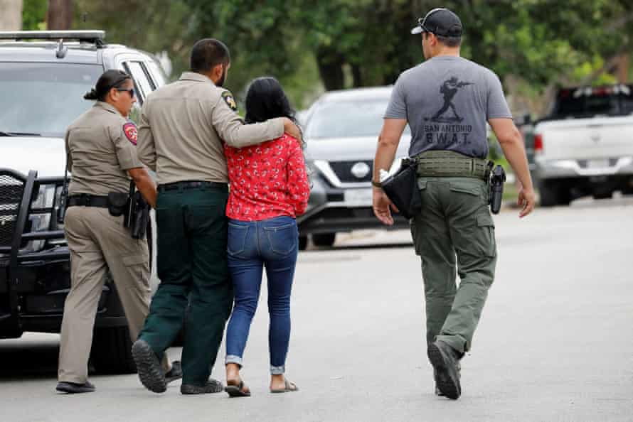 Officers escort a woman down a street near the scene of the shooting.