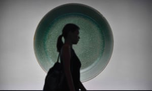 A visitor walks past a backlit photo of a 1,000-year-old Chinese bowl which sold for $37.7m.