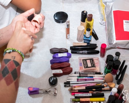 A range of lipsticks, eyeliners and other makeup products laid out on a floor