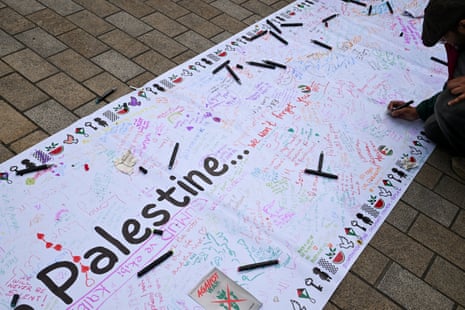 Ένα άτομο υπογράφει ένα πανό στέλνοντας ένα μήνυμα συμπαράστασης στον λαό της Παλαιστίνης κατά τη διάρκεια της πορείας.