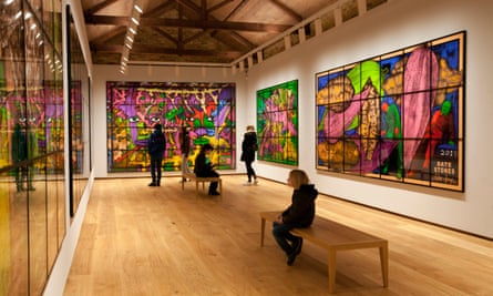 Photo looking doen the length of the gallery, which has large and very colourful art on all three visible walls, evidently part of a series