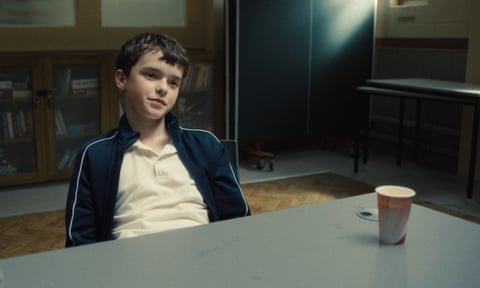 A teen boy looks smug while sitting in a police questioning room