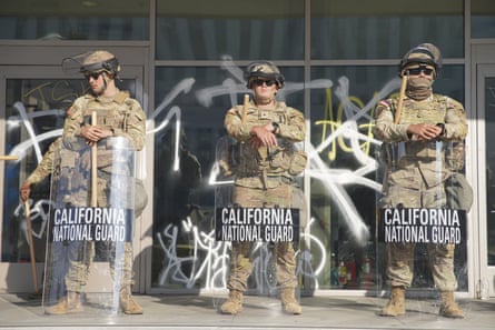 People in camouflage behind shields that say California national guard.