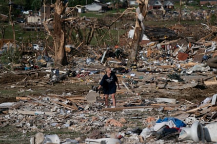 a woman stands in the middle of debris
