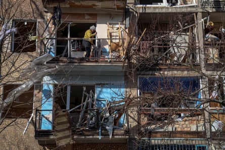 A resident cleans up her apartment in a building damaged during a Russian military strike in Kurakhove