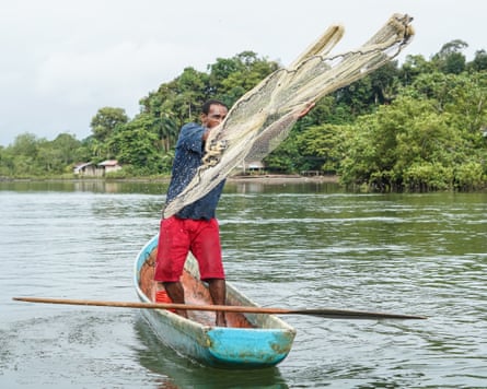 An Afro-descendant man throwing a net to fish in the river.