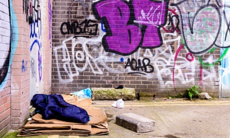 Sleeping bag and cardboard boxes left behind by a rough sleeper in an alleyway.