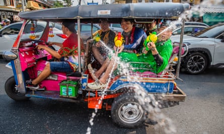 People spray water from a tuk-tuk