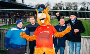 Joel Golby como mascota de fútbol Bertie the Beaver con fanáticos en Hampton & Richmond Borough FC