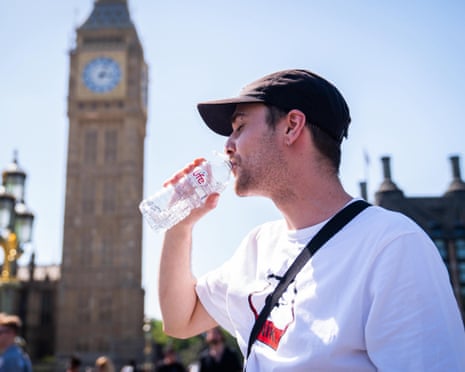Man drinks from a water bottle, with the Palace of Westminster in the background